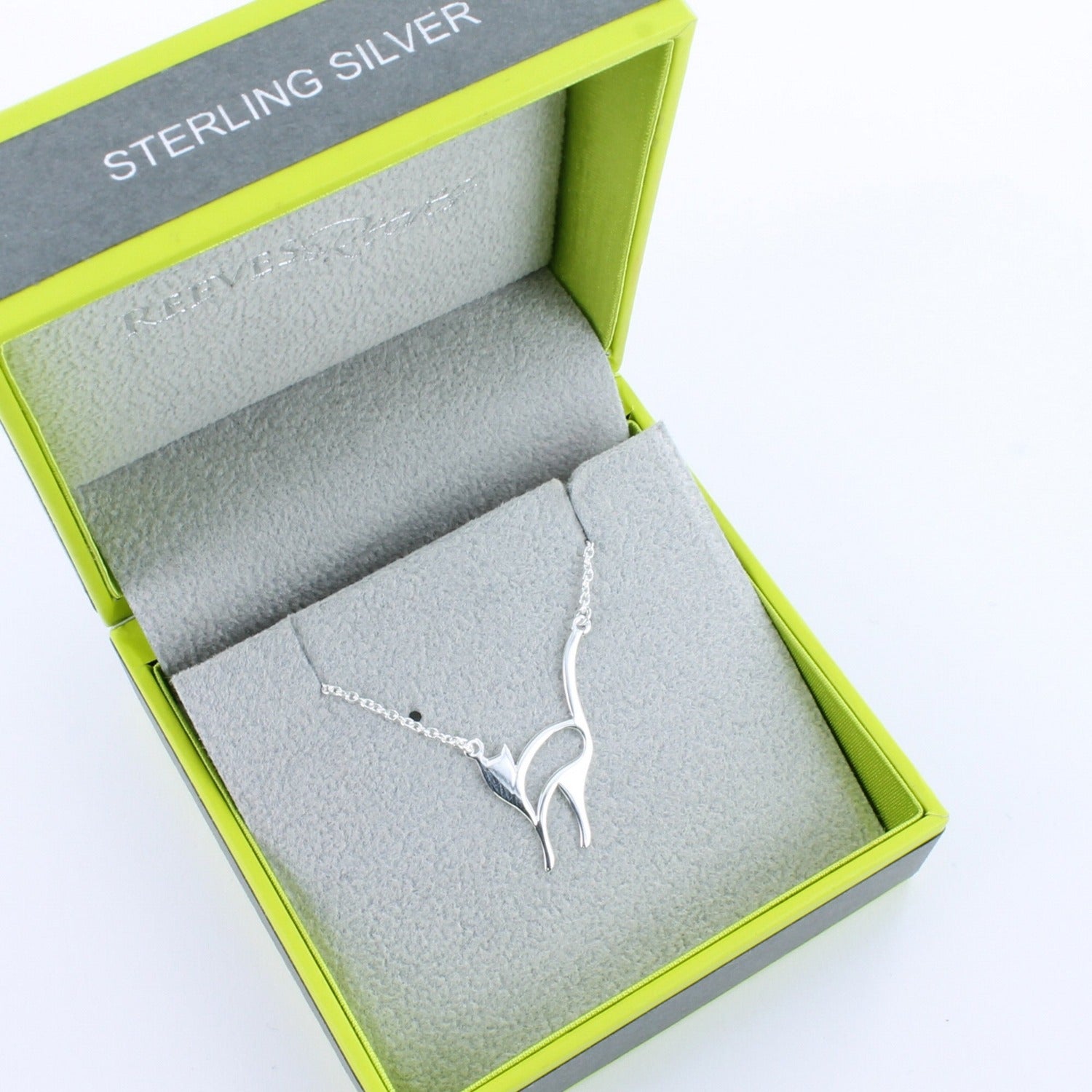 A sterling silver snooty cat necklace, in flat silhouette style and shown in a Reeves & Reeves grey and green branded gift box.