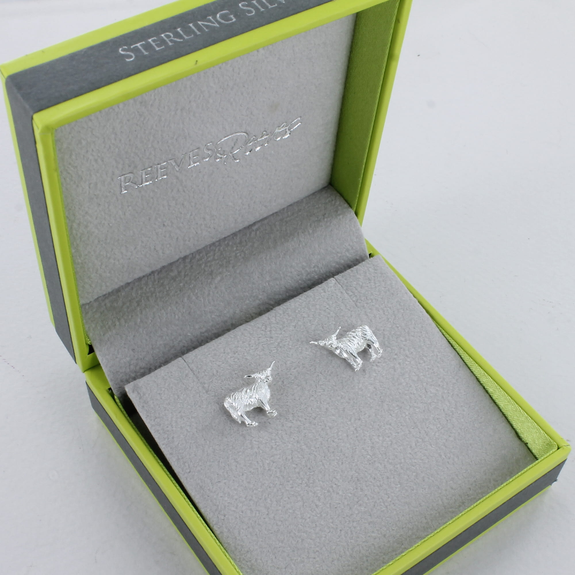 A pair of sterling silver highland cow stud earrings, shown in a Reeves & Reeves gift box.