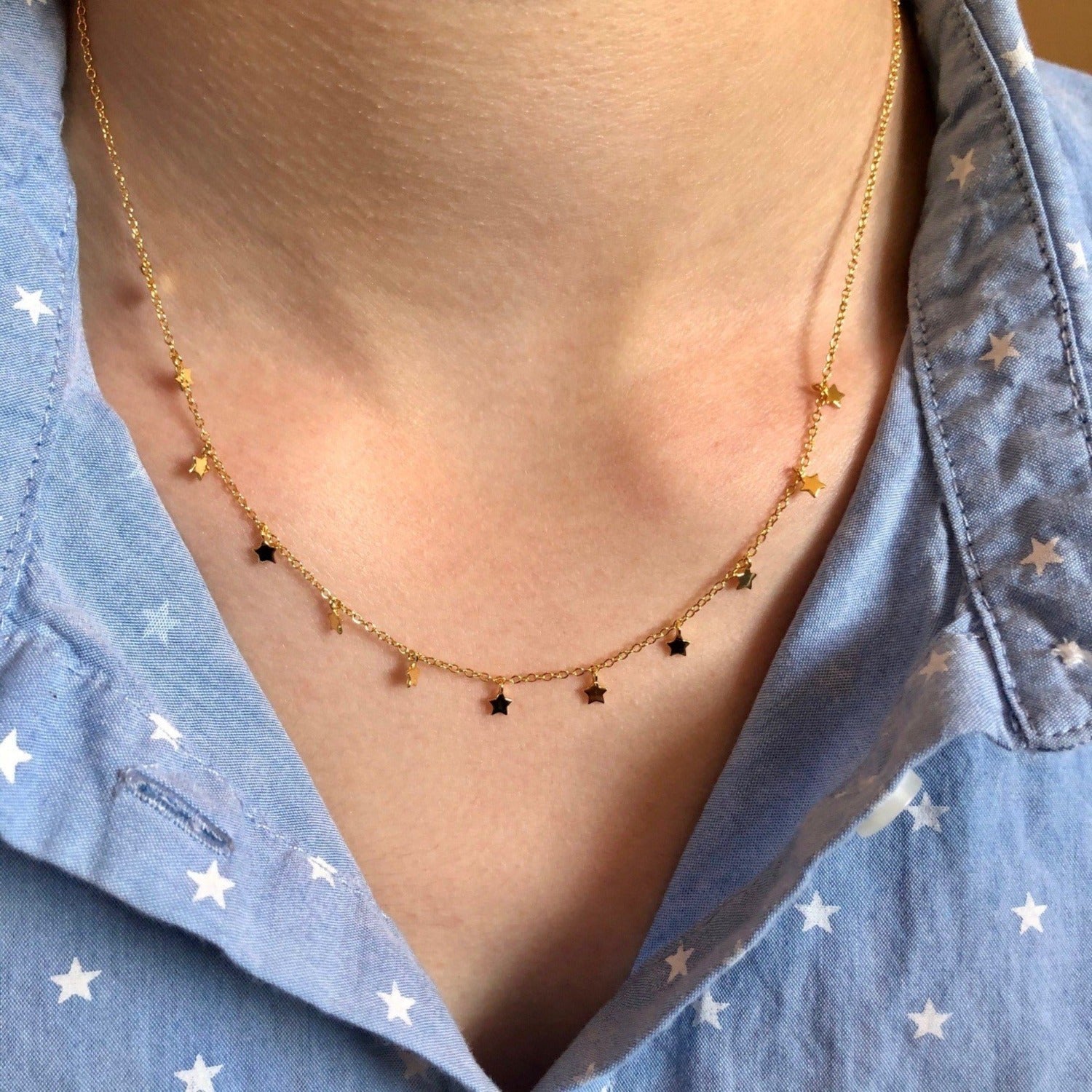 A mode wears a sterling silver and gold plated chain necklace with twelve 2D stars spread evenly along the chain.