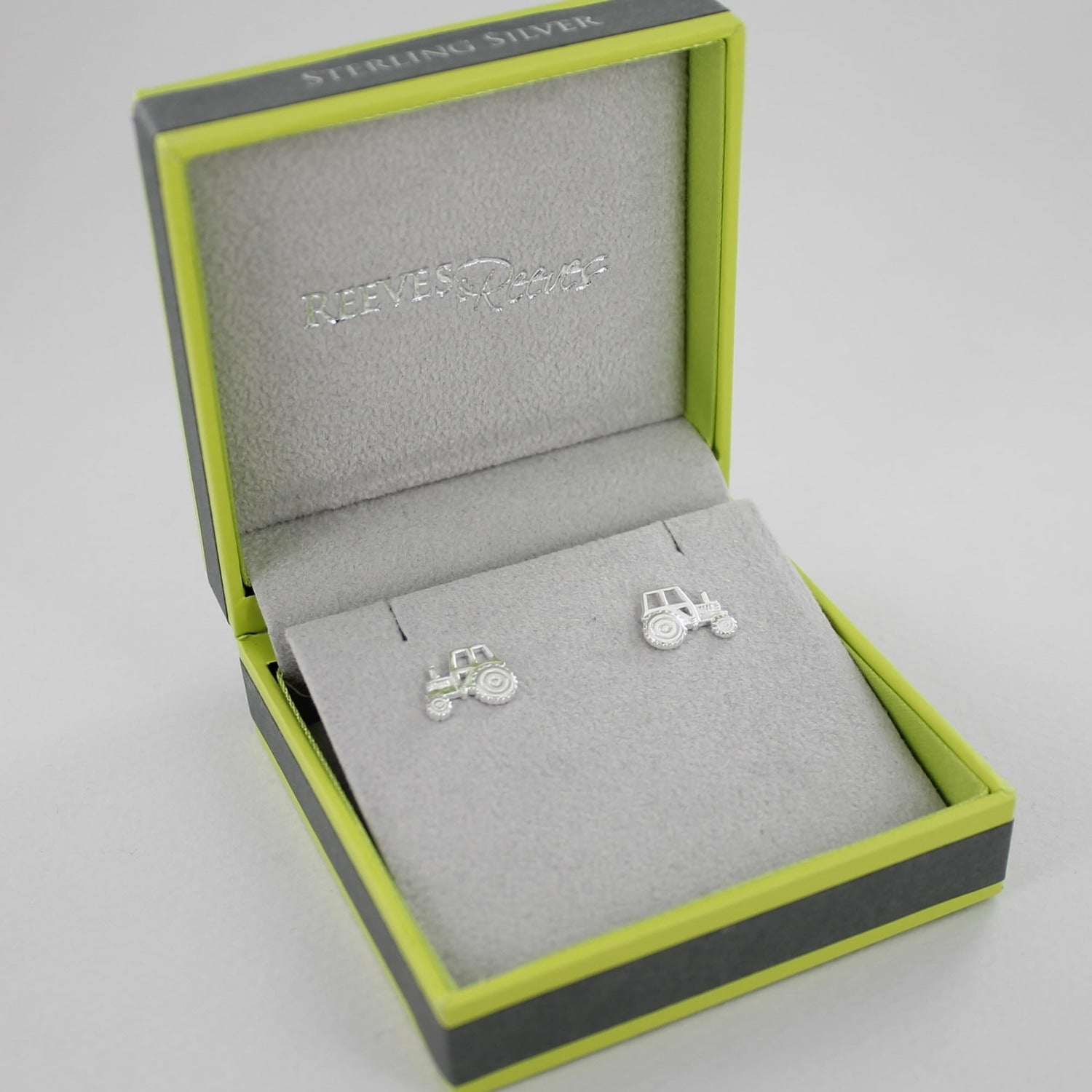 A pair of two dimensional, sterling silver tractor stud earrings, shown in a Reeves & Reeves gift box.