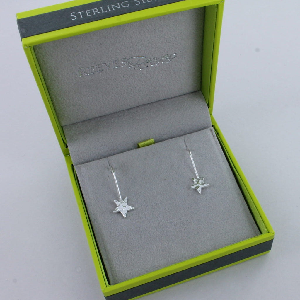A pair of sterling silver drop earrings with hammered stars hanging from the bottom. Shown in a Reeves & Reeves gift box.