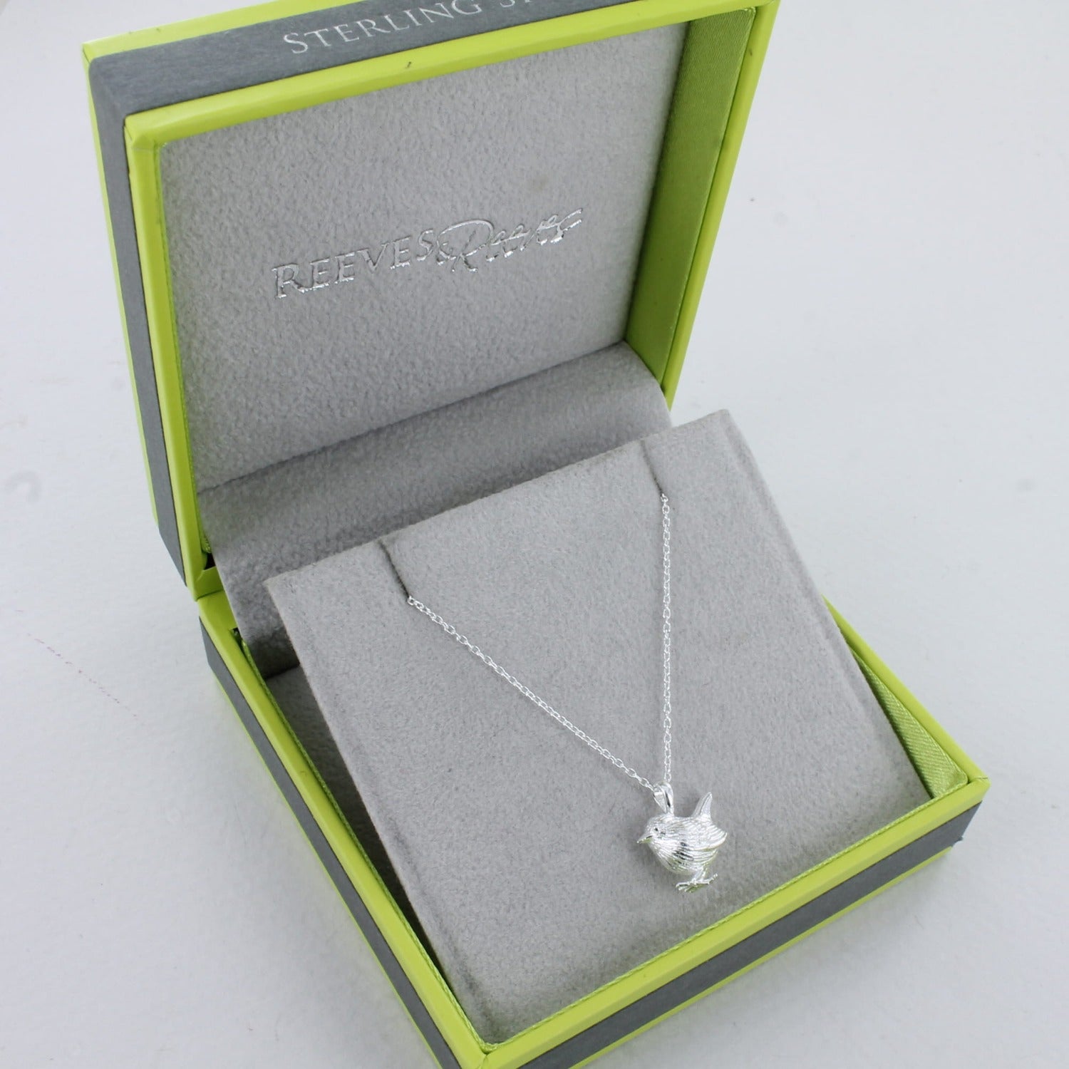 Sterling Silver Wren Necklace in a Reeves & Reeves branded gift box. The box is brand colours, grey and green, with a grey insert and Sterling Silver on the outside of the box.