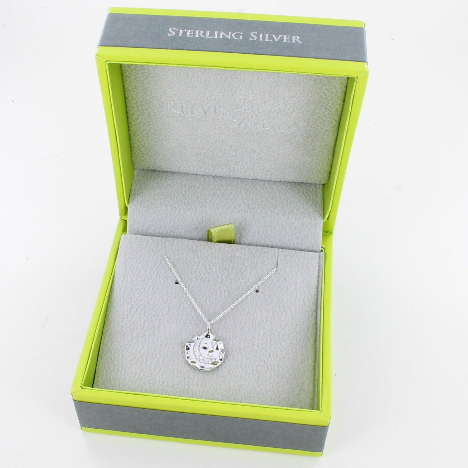 Silver disc necklace with a moon in the centre, filled with cubic zirconia stones. Hangs on an adjustable silver chain and in a Reeves & Reeves grey and green branded box.