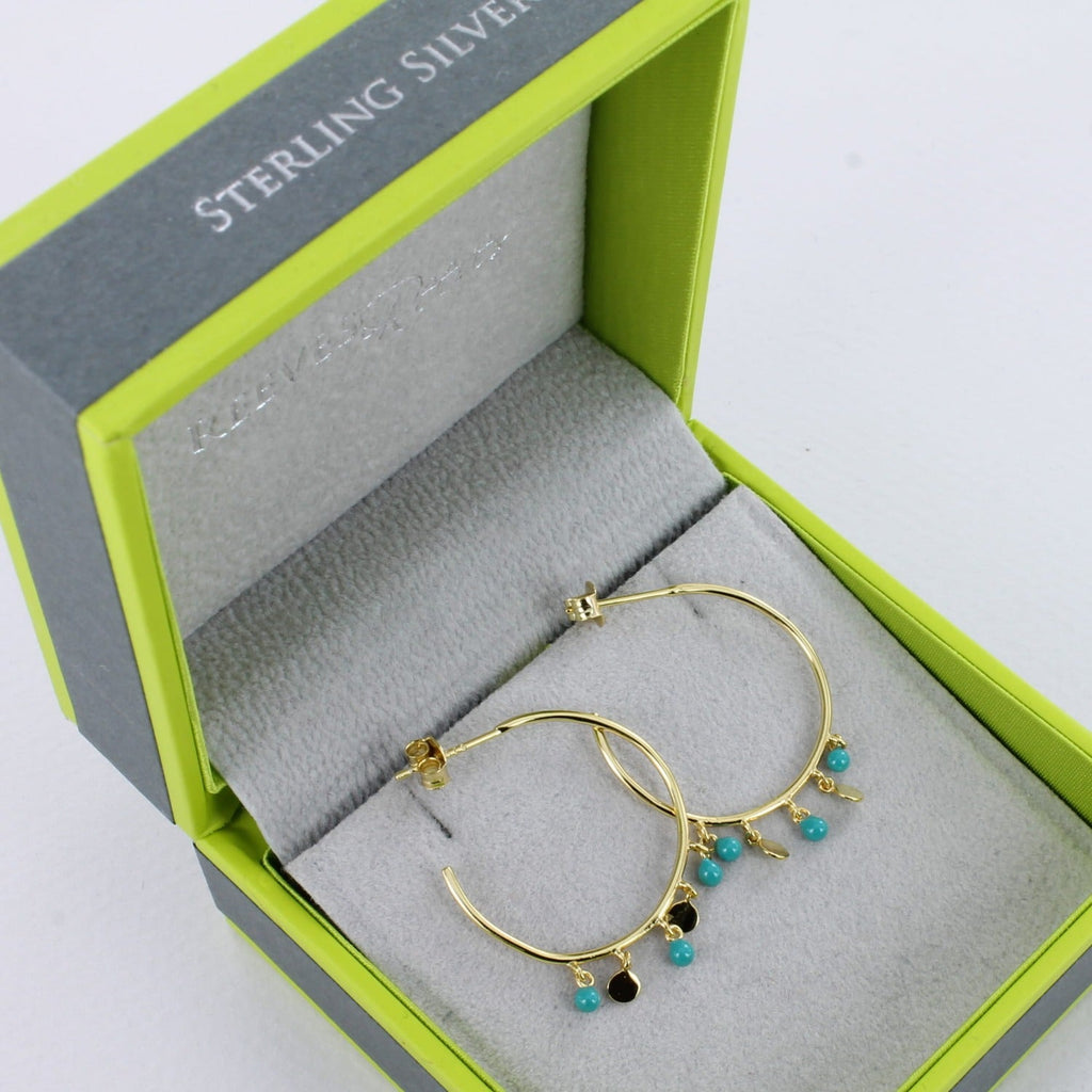 A pair of sterling silver and 18ct gold plated large hoops with three turquoise beads hanging from the bottom with two high shine gold discs in-between. Shown in a Reeves & Reeves gift box.