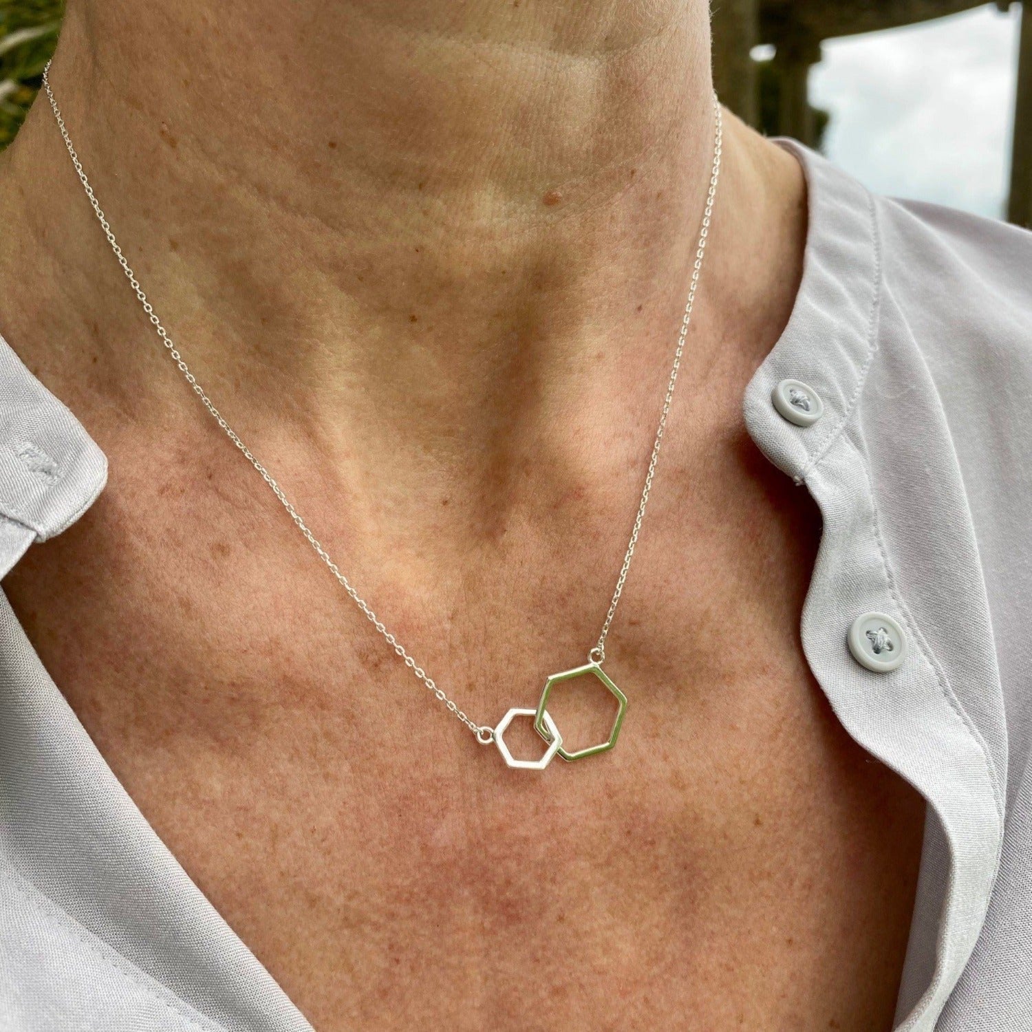 Silver Hexagons of two different sizes, interlinked and sat centrally on a fine silver adjustable chain. Worn on a models neck.
