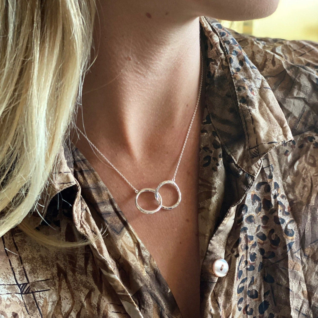 Sterling Silver interlocking rings necklace, one with a hammered finish and hung centrally on a silver adjustable chain.