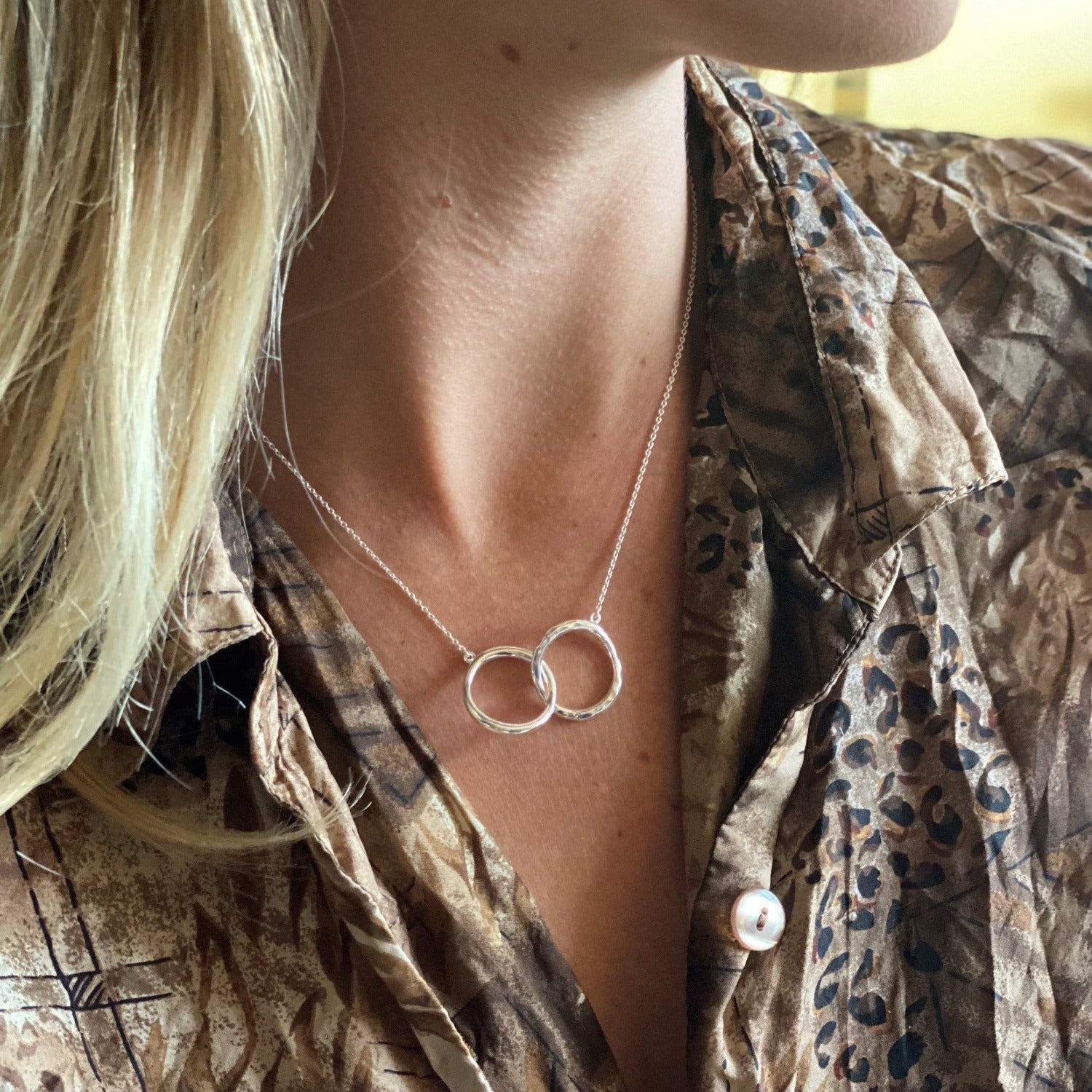 Sterling Silver interlocking rings necklace, one with a hammered finish and hung centrally on a silver adjustable chain.