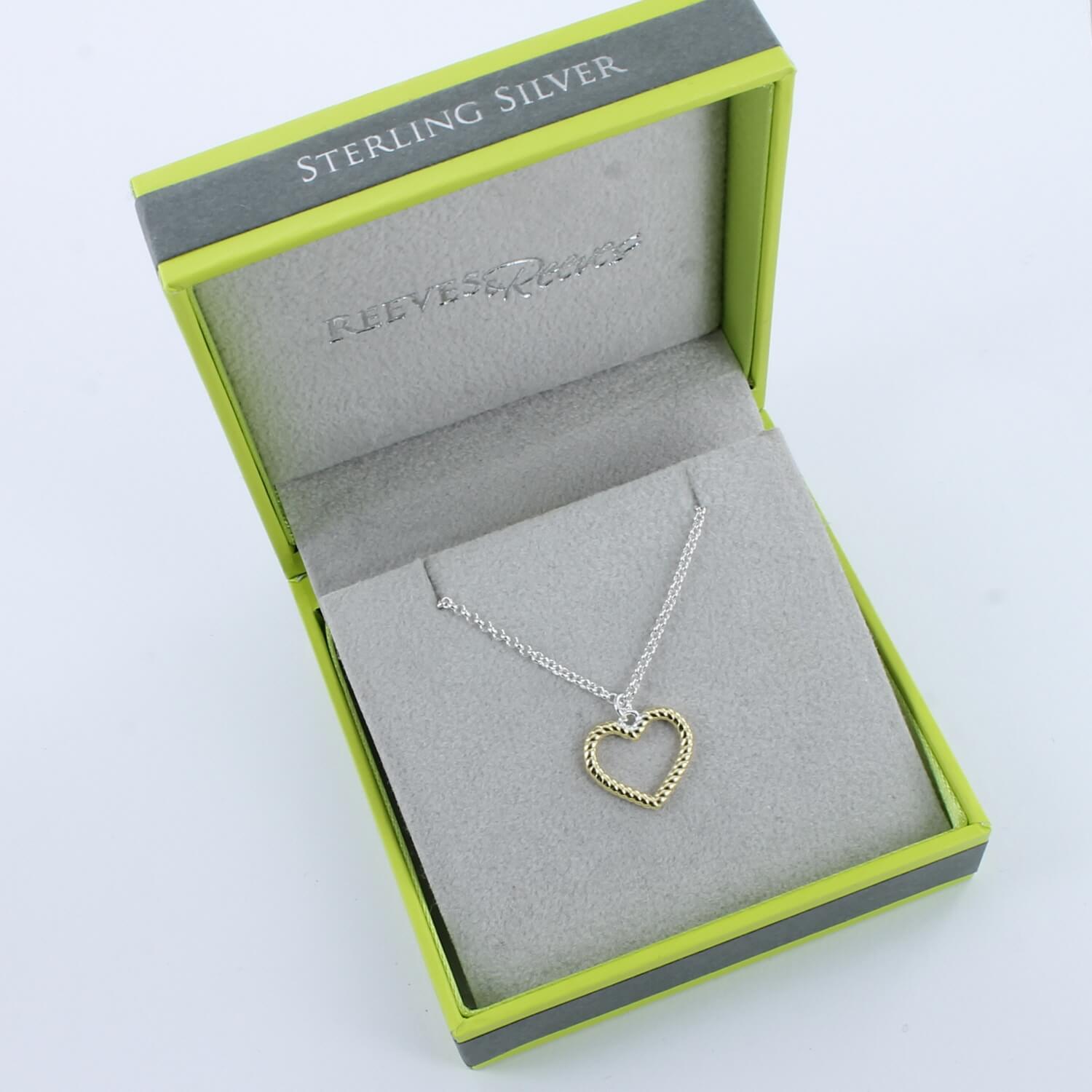 A heart silhouette pendant in sterling silver and gold plating, on a fine silver adjustable chain and shown in a Reeves & Reeves grey and green gift box.